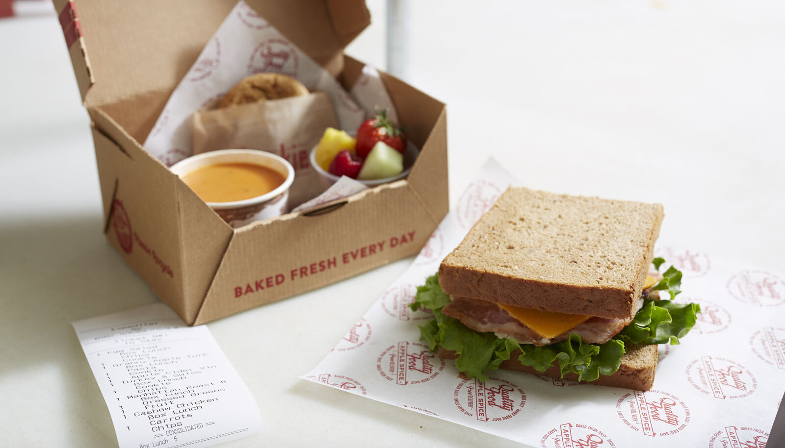 boxed lunch with multiple food items inside and a sandwich next to it